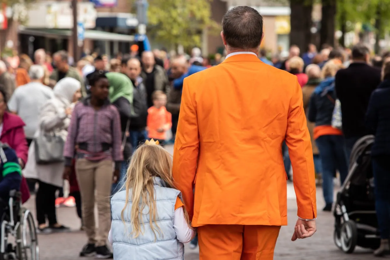 kings day crowd in amsterdam with man walking away from the camera in an orange suit