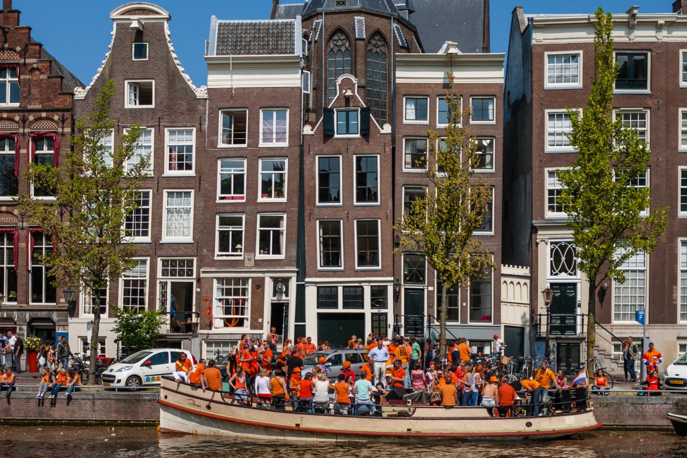 boat full of orange-dressed people celebrating kings day in amsterdam april 27