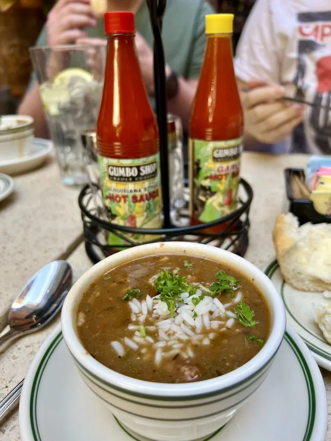 bowl of new orleans gumbo with bottles of ot sauce visible behind it