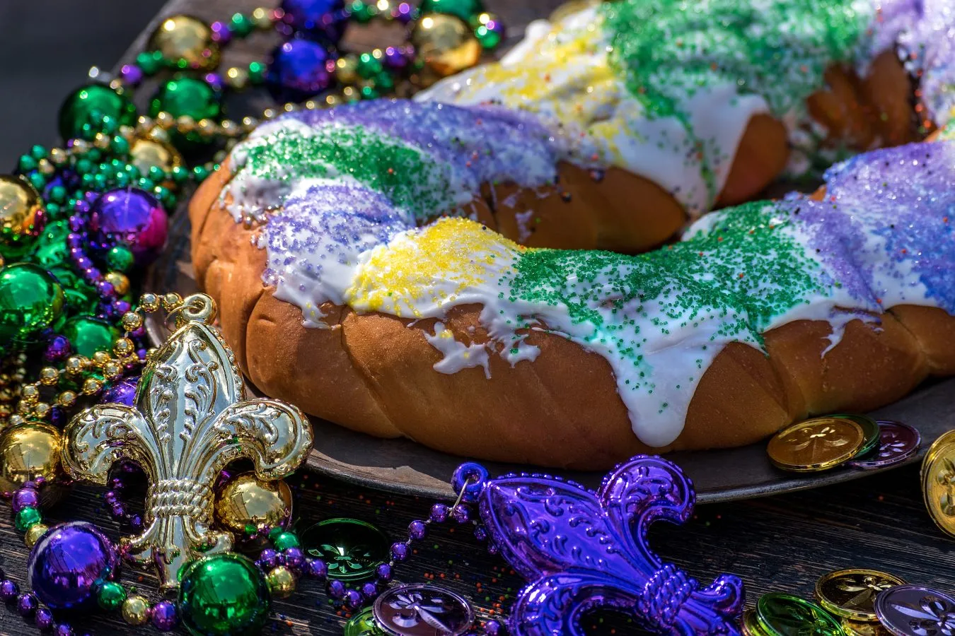 mardi gras king cake iced and surrounded by mardi gras beads