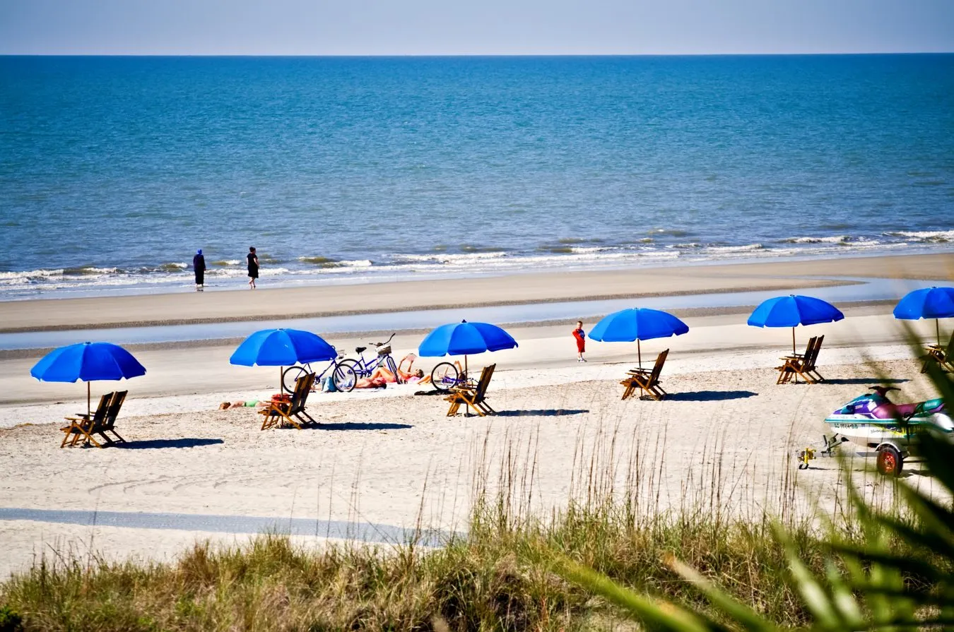 blue beach umbrellas set up along the shore at hilton head island, one of the best beach towns on the east coast usa