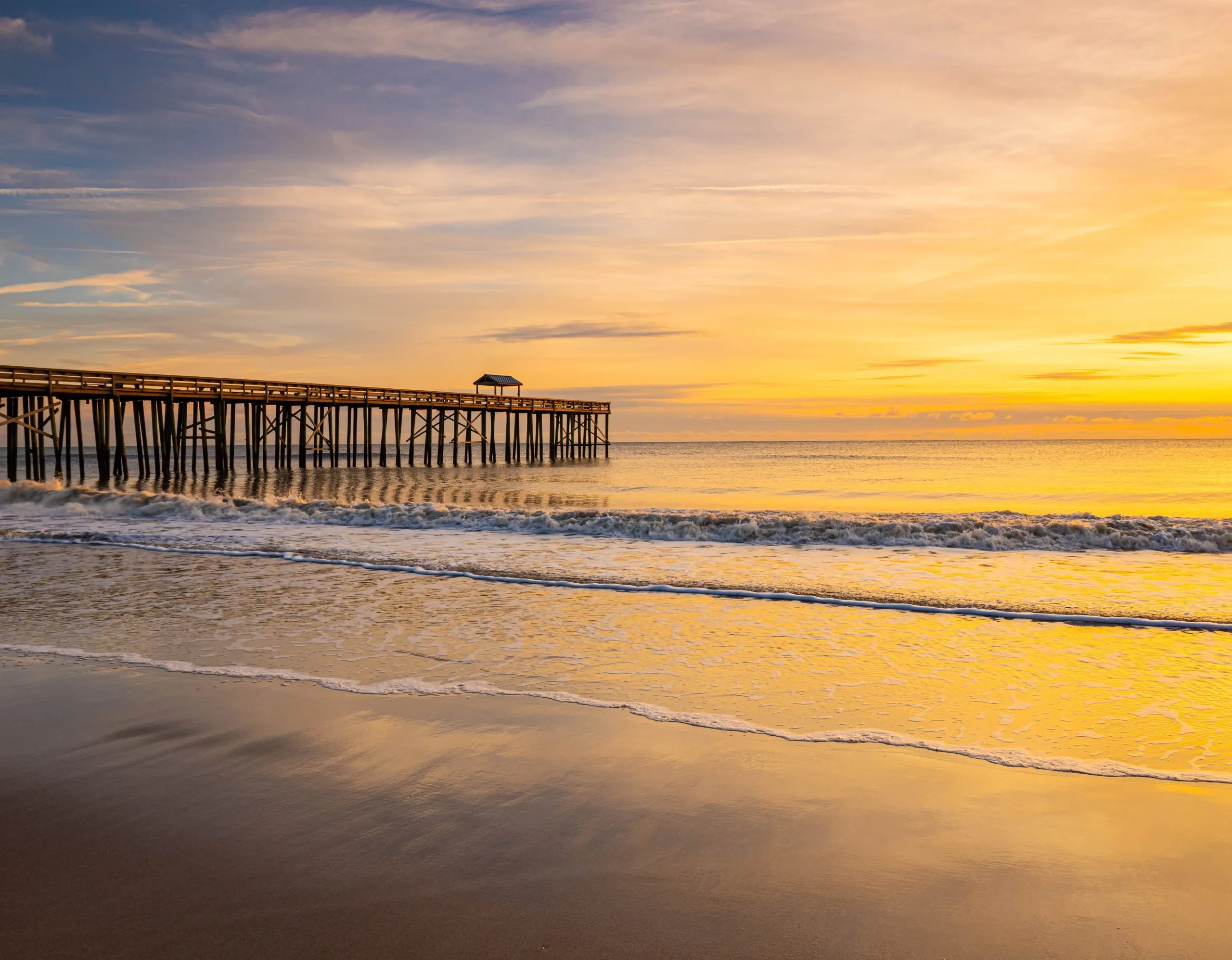 sunrise over the ocean and wooden pier at fernandina beach, one of the many beautiful east coast beach towns