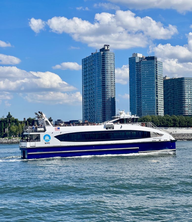 nyc ferry traveling through the east river with roosevelt island visible in the background