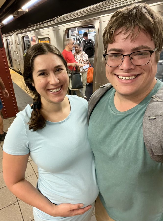 kate storm and jeremy storm taking a selfie with a nyc subway behind them