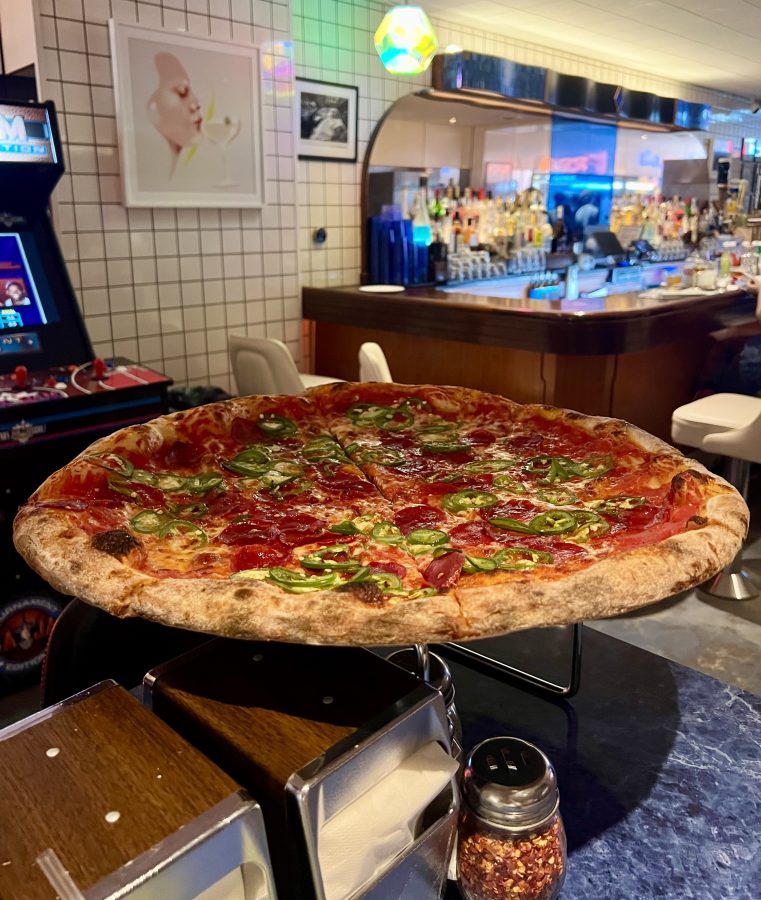 large pizza with pepperonis and jalapenos on it pictured in scarrs pizzeria in nyc