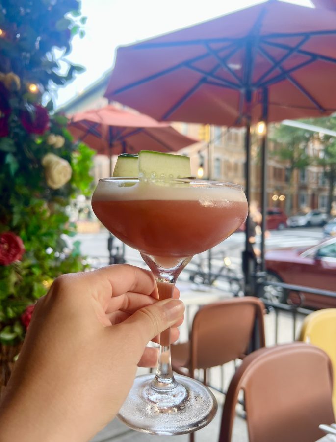 photo of pink cocktail being held up in front of brooklyn patio pasta louise