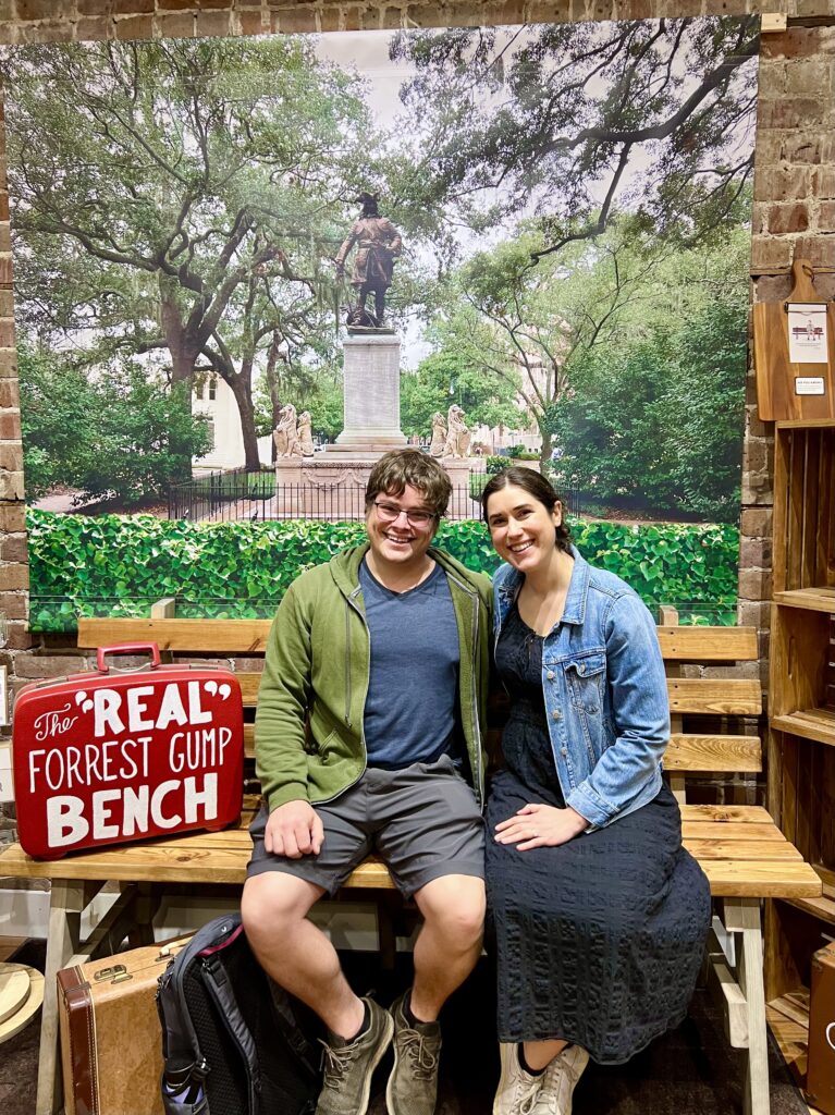 kate storm and jeremy storm sitting on a replica forest gump bench in savannah weekend getaway